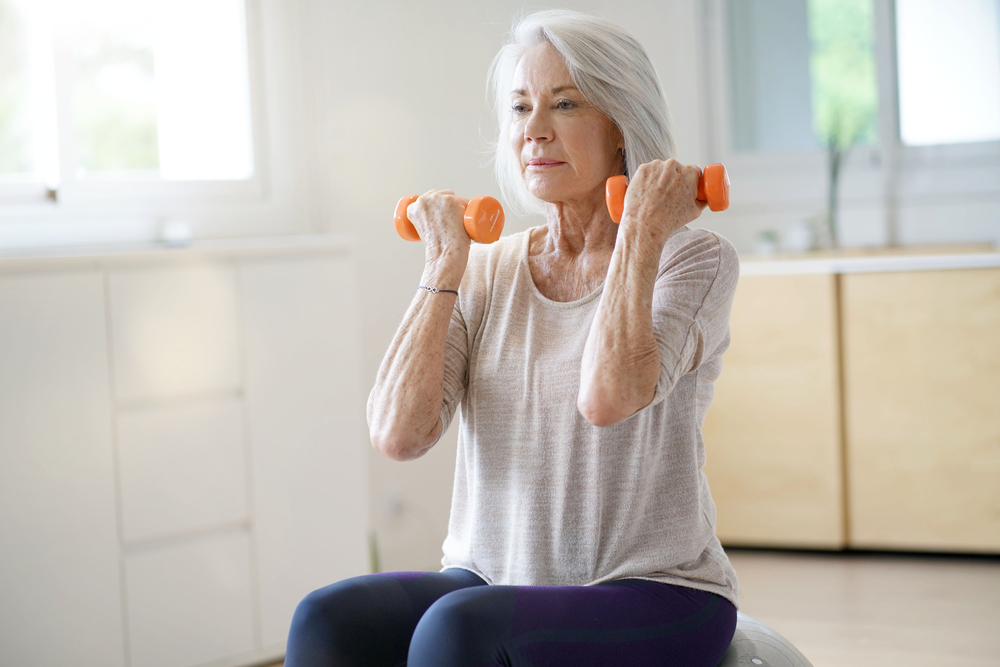 Attractive Elderly Woman Exercising At Home With Swiss Ball